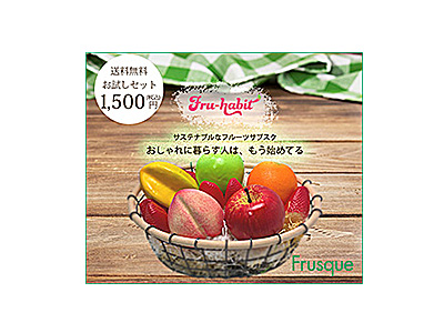 木製テーブルの上に並べられた果物バスケットのバナー広告画像。背景には緑と白のチェック柄クロスがあり、ナチュラルで温かみのあるデザイン。